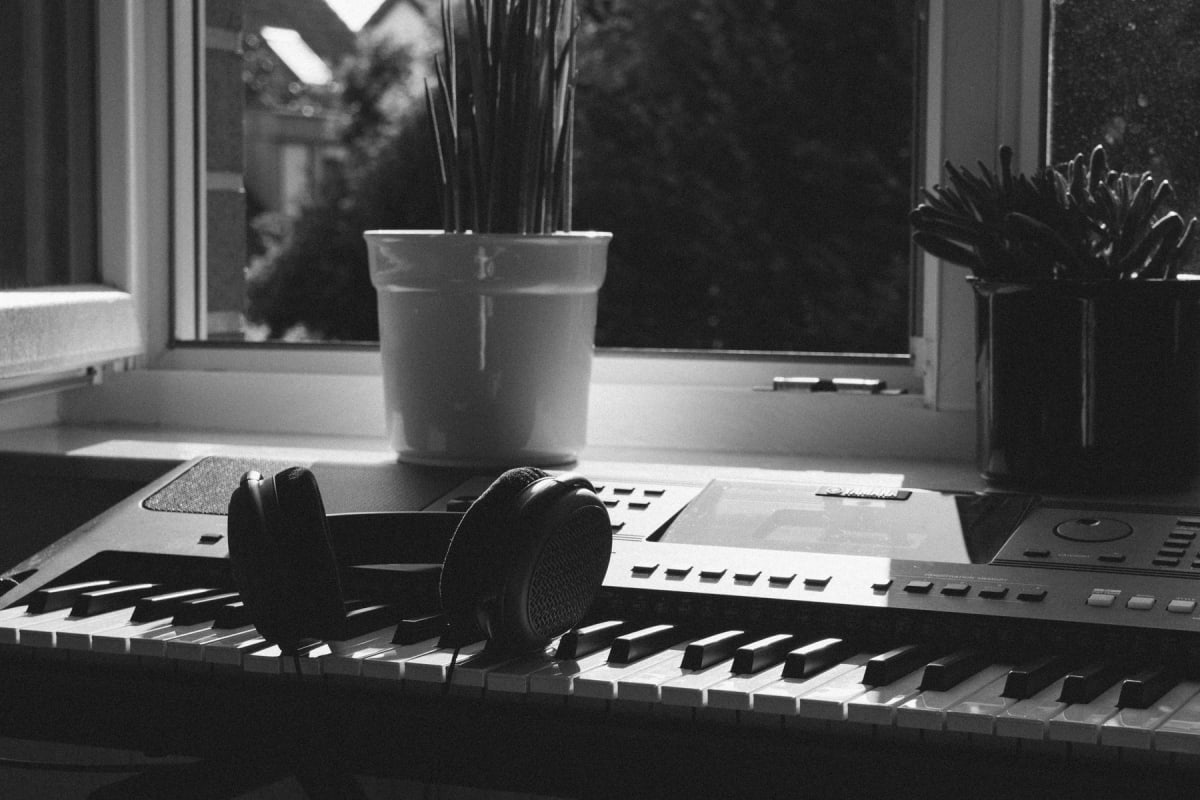 Wired headphones resting on an electronic keyboard beside a window