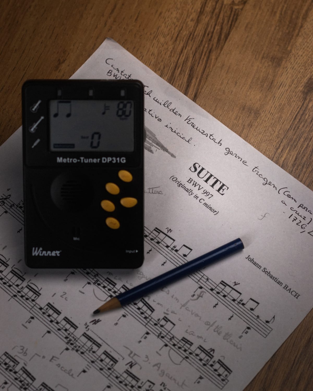 Physical electronic metronome and pencil on annotated Bach sheet music
