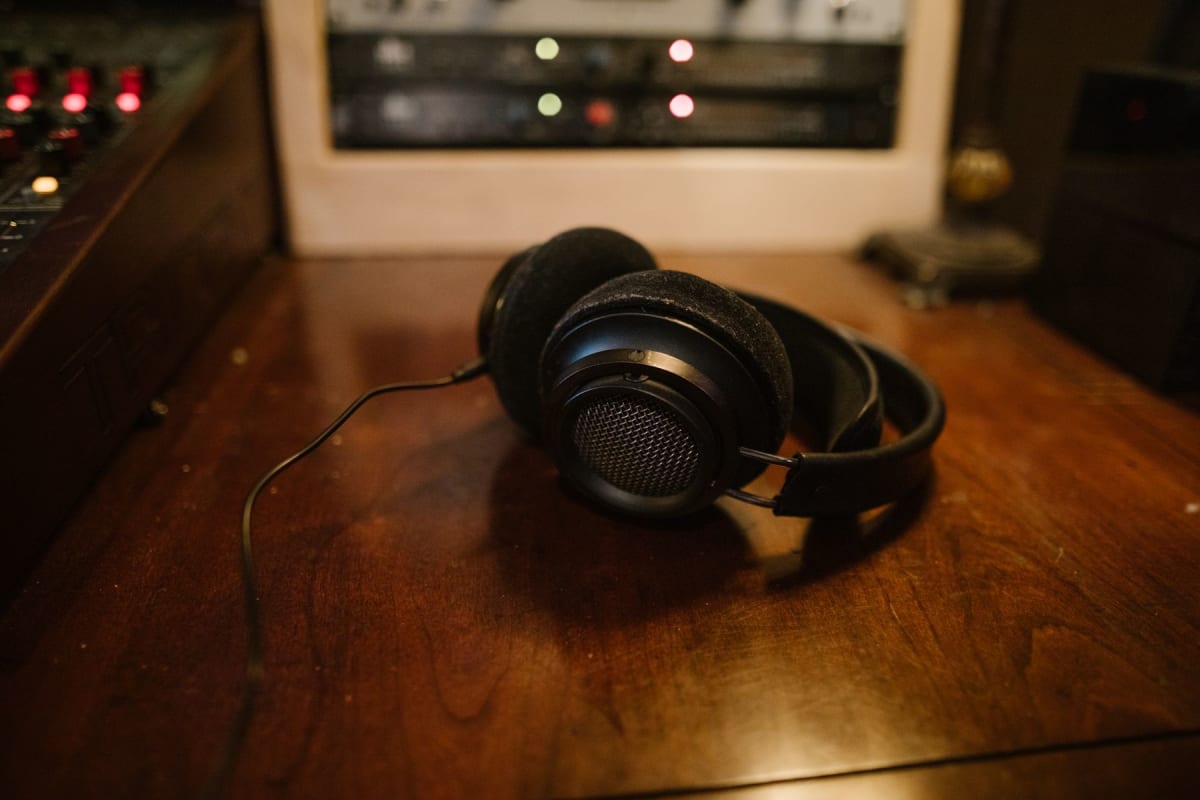 Wired open-back headphones resting on a wooden desk in a recording room