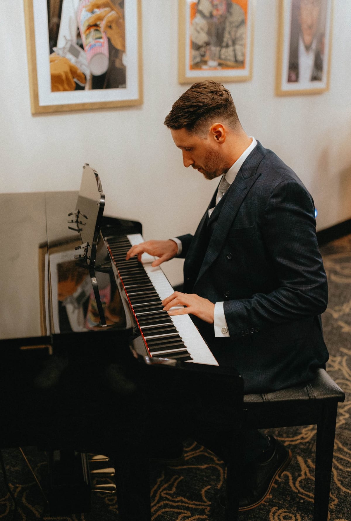 Side view of a pianist seated on a rectangular bench at an upright piano
