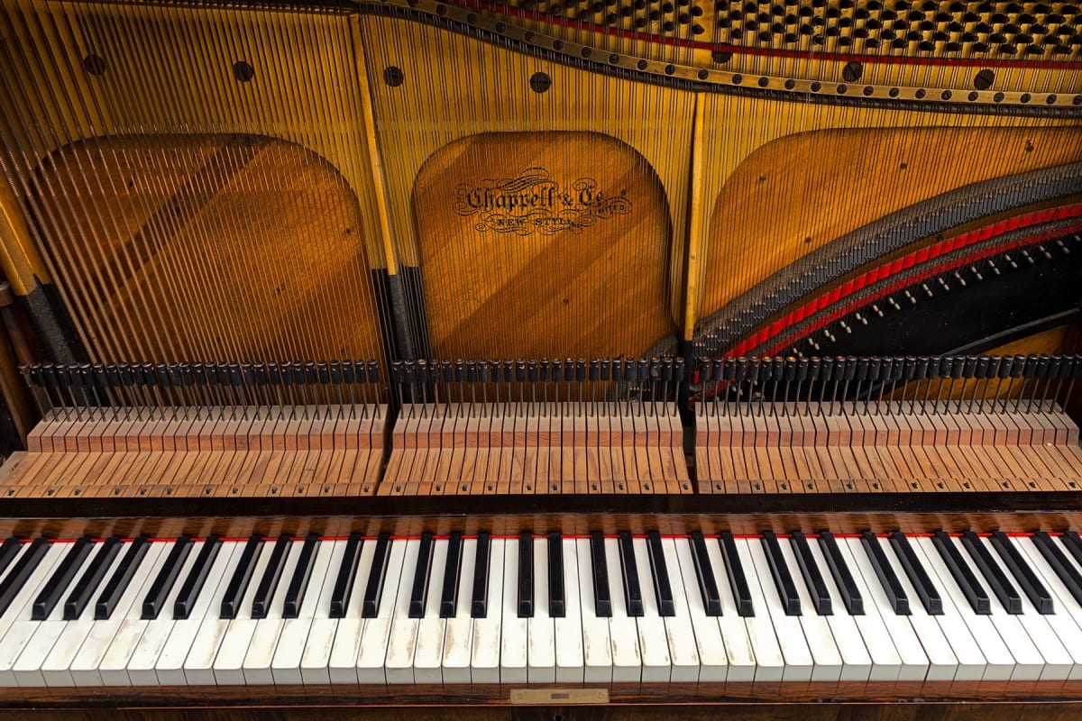 Exposed keys, action, and strings inside an upright acoustic piano