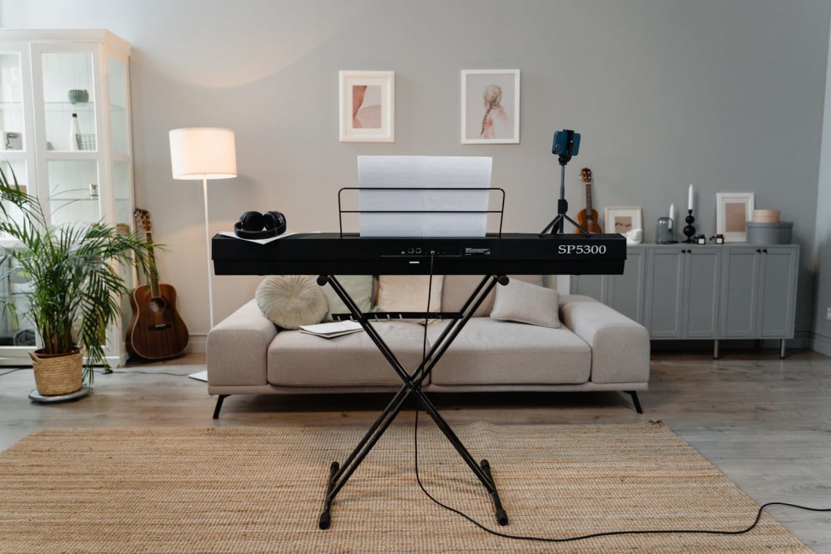 Digital piano on an X-stand with a cable running across the rug
