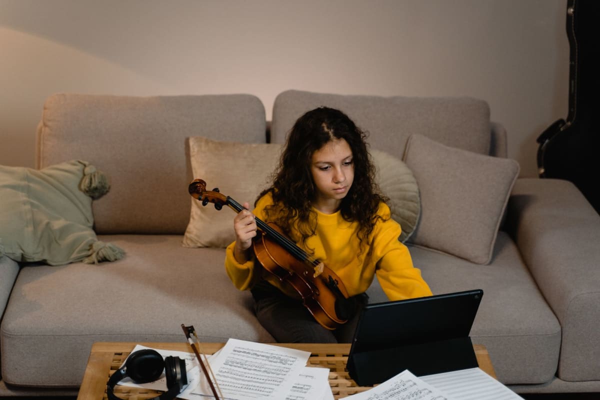 Violinist pausing with her instrument to tap a tablet during practice