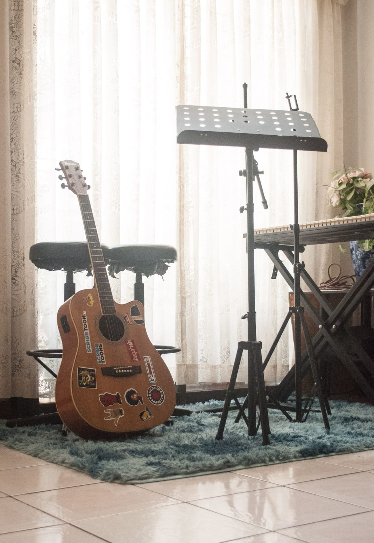 Portable keyboard on an X-style stand beside a bench and music stand in a home practice corner