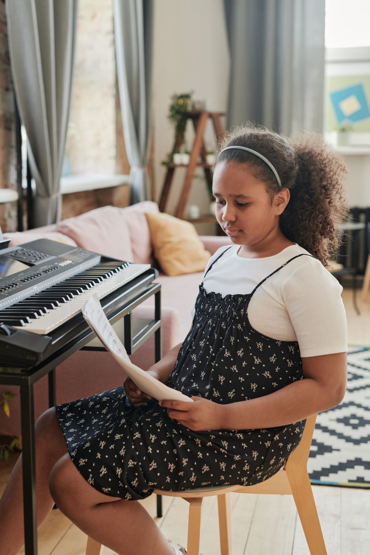 Seated keyboard student beside an open-frame stand with clear space around her knees