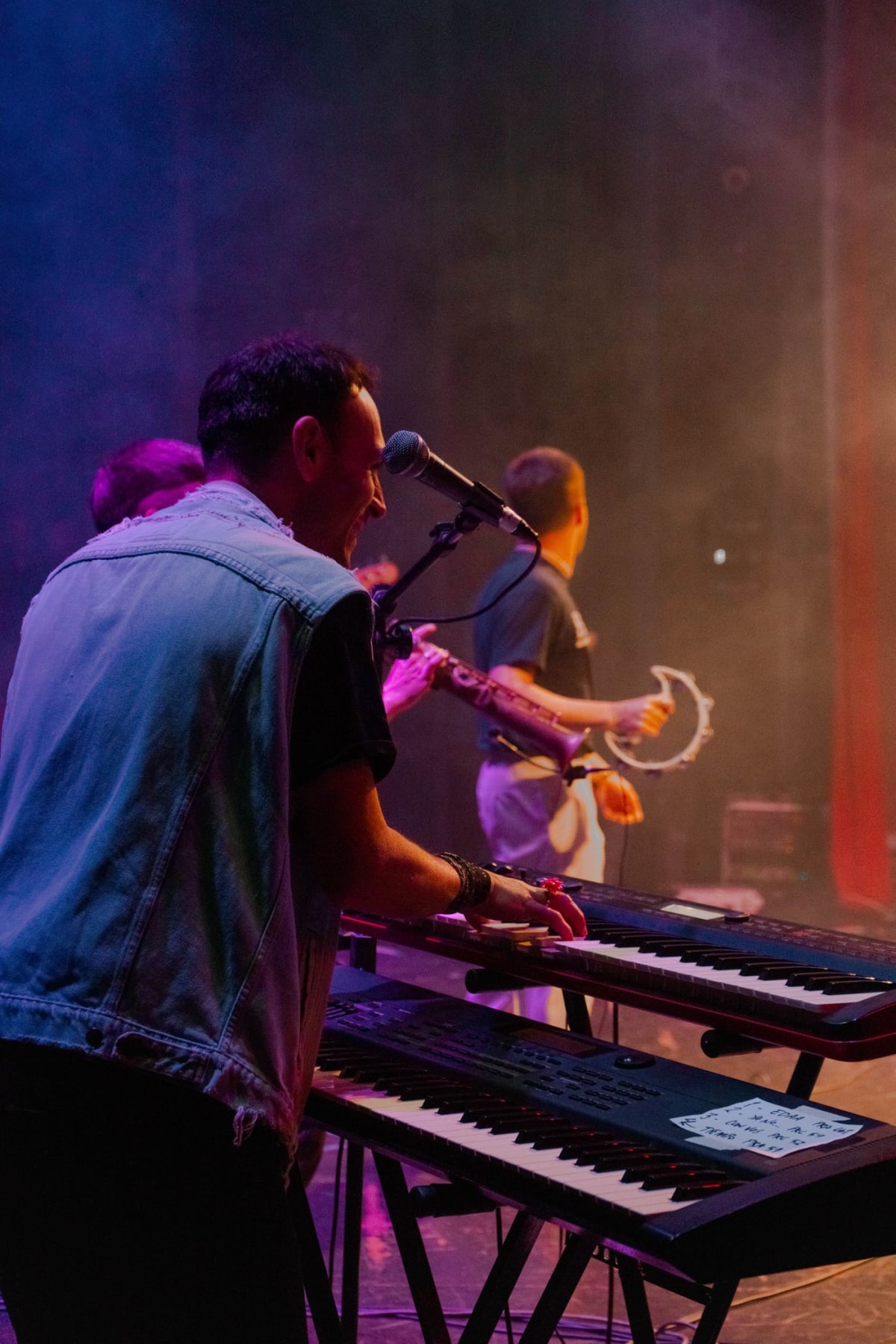 Keyboardist performing on a two-tier keyboard setup under stage lights