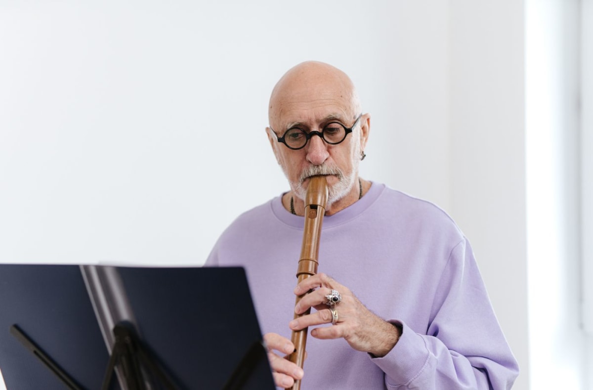 Flute player reading music from a stand in a bright home practice room