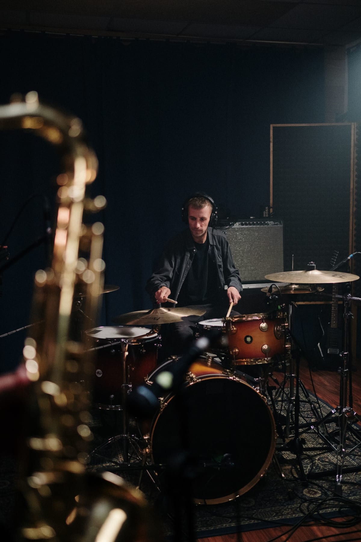 Drummer wearing studio headphones while playing a kit during rehearsal