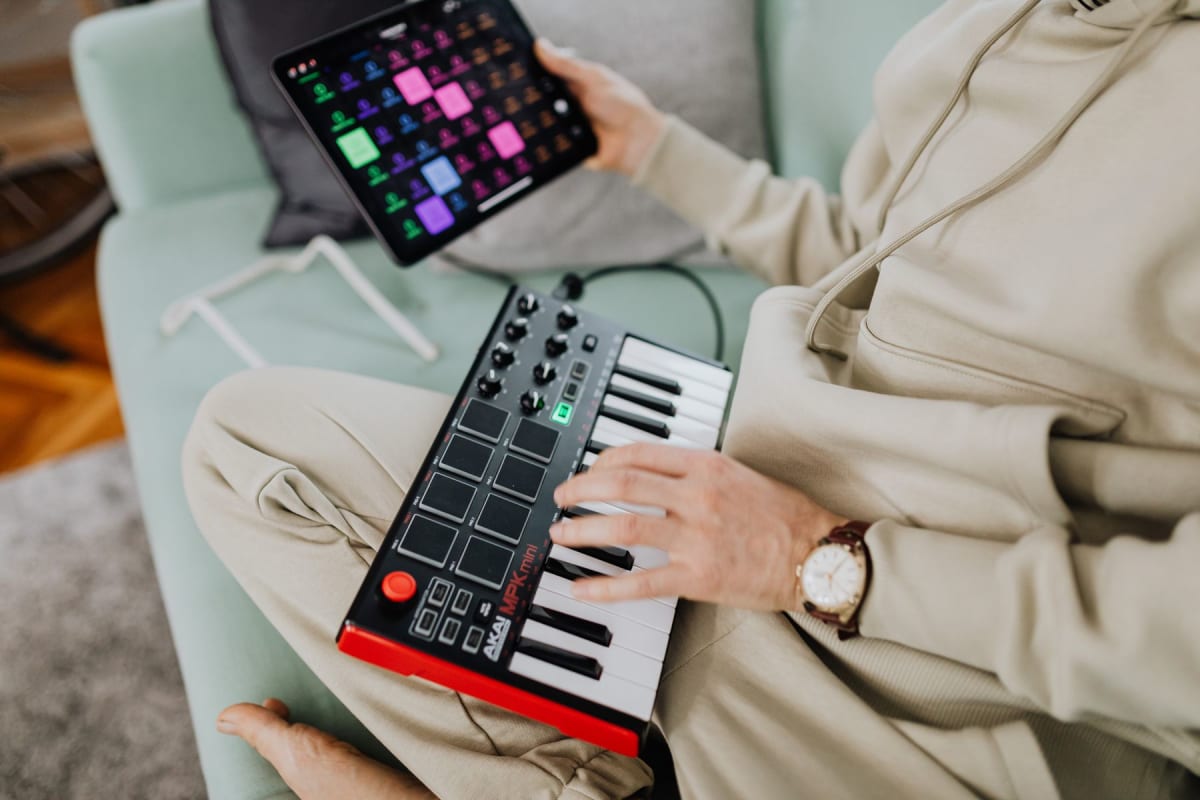 Compact MIDI keyboard being played beside a tablet running music software