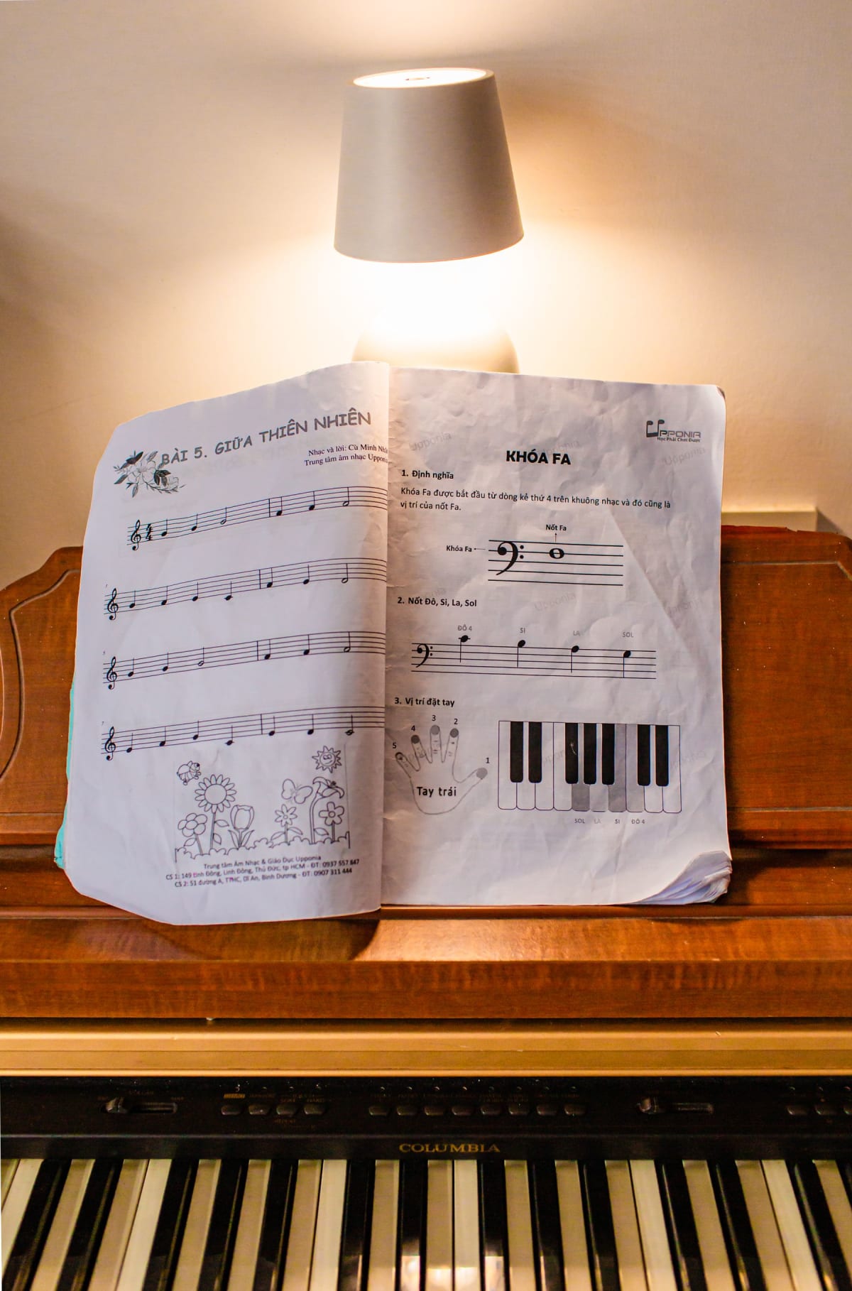 Open sheet music on an upright piano with a warm lamp glowing behind the pages