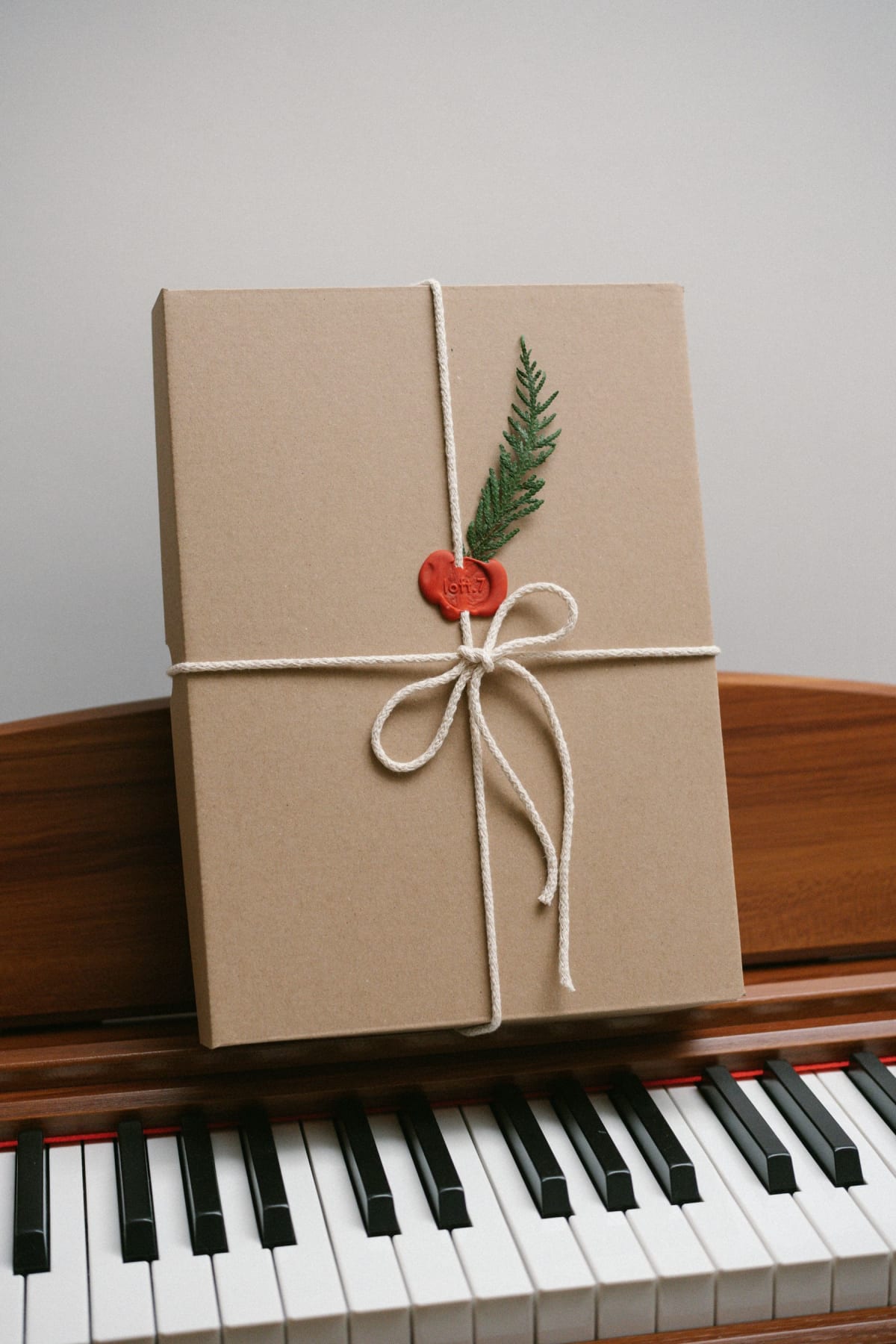 Brown paper gift tied with string and resting above the keys of an upright piano