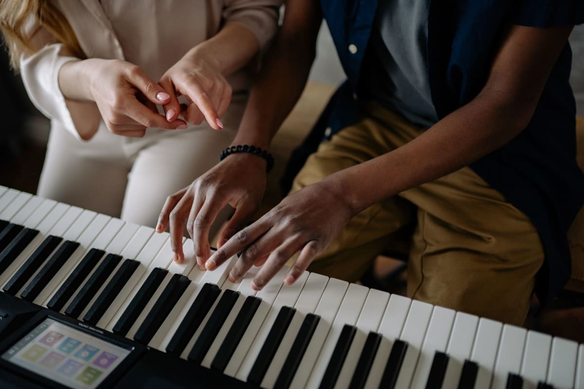 Piano teacher pointing while a student plays a digital keyboard