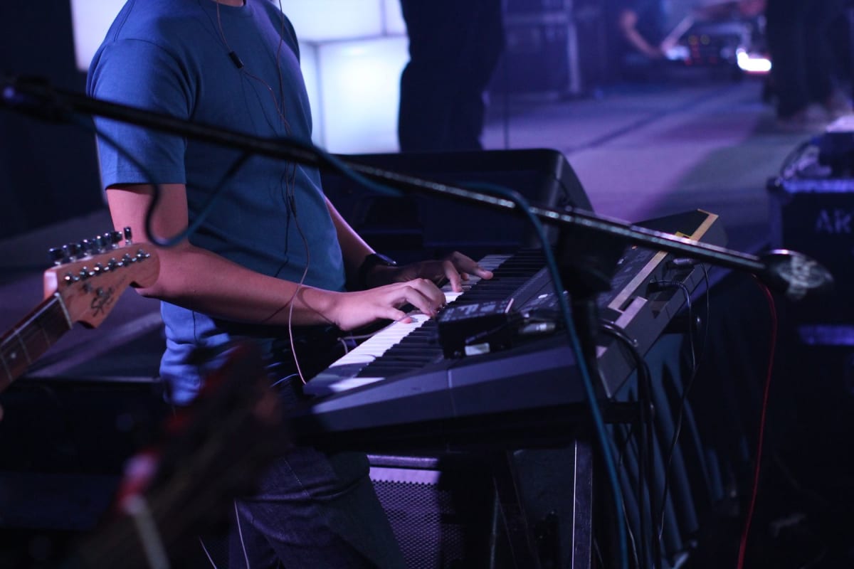 Keyboard player performing with a band on a live stage