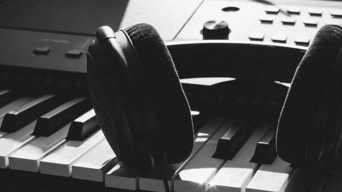 Black over-ear headphones resting across an electronic keyboard
