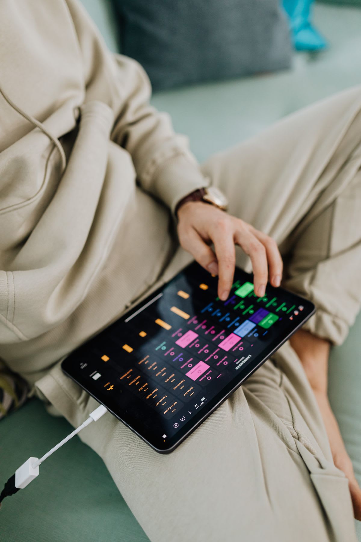 A person using music software on a tablet with a wired adapter connected