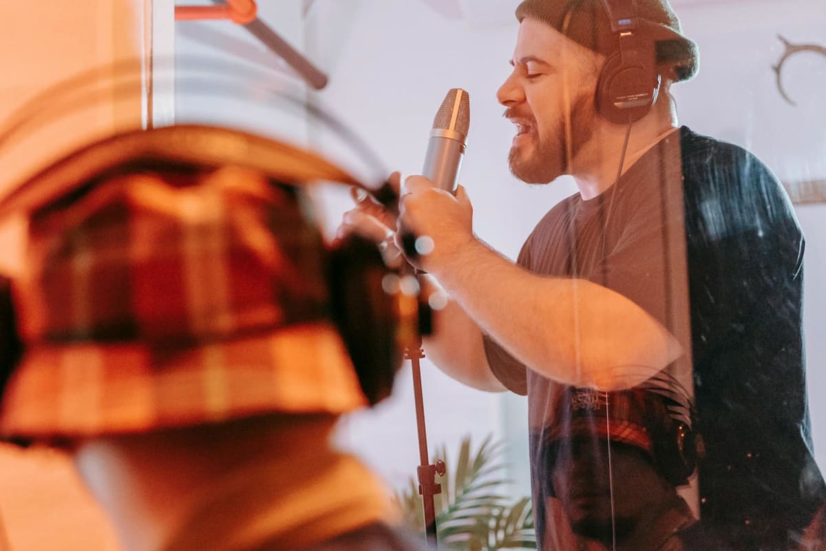 Singer wearing headphones and recording into a microphone in a studio