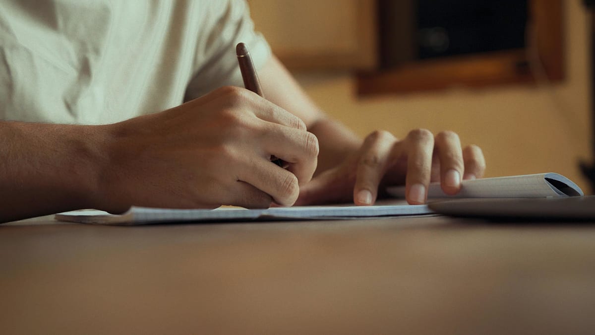 Hands writing notes in a notebook during focused work