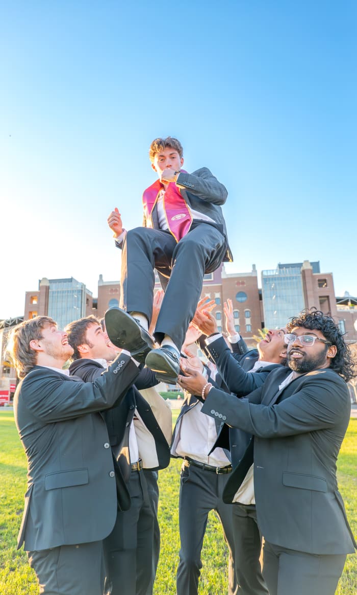 FSU grads tossing a graduate in the air