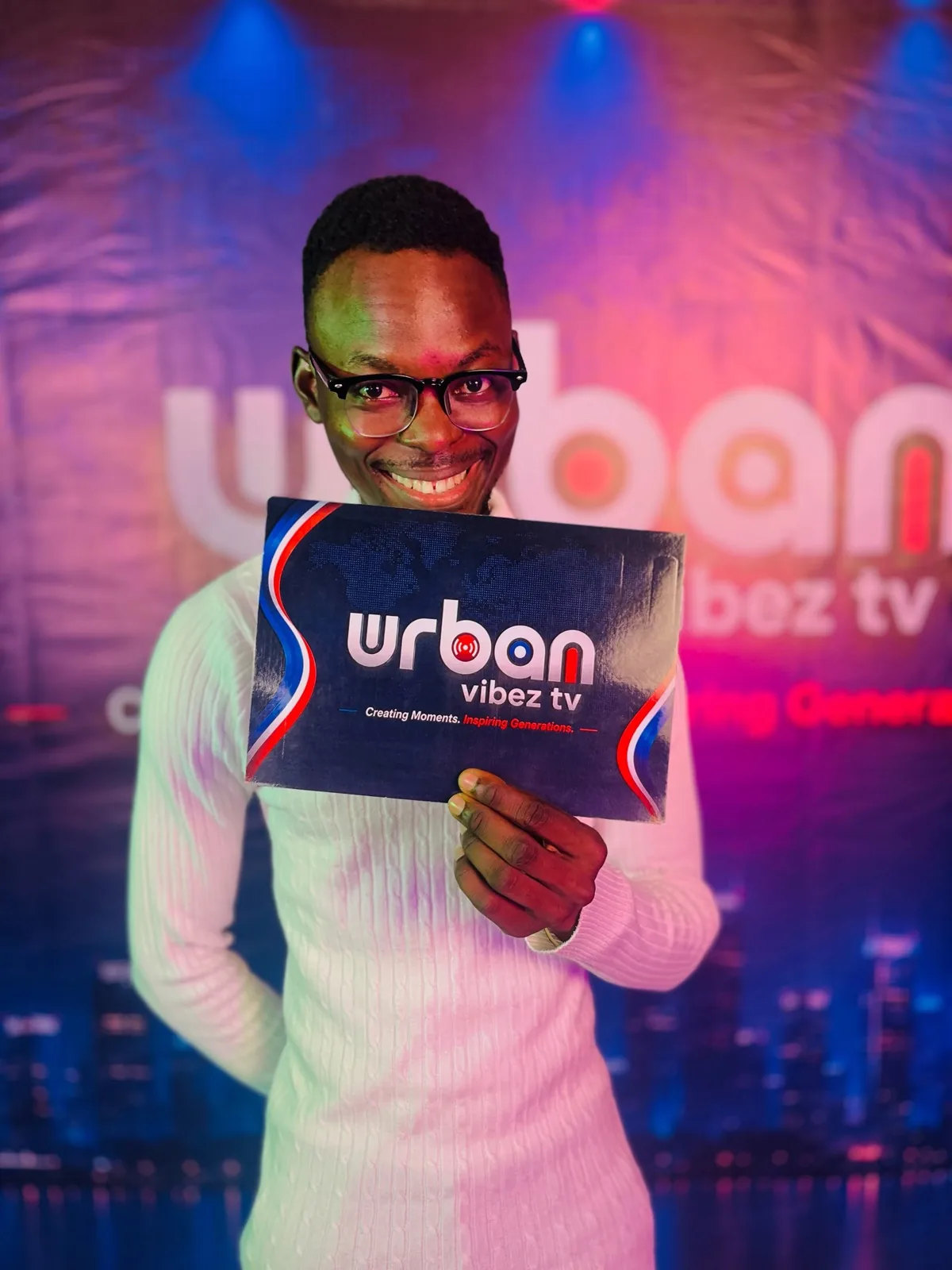 Host holding the Urban Vibez TV logo placard