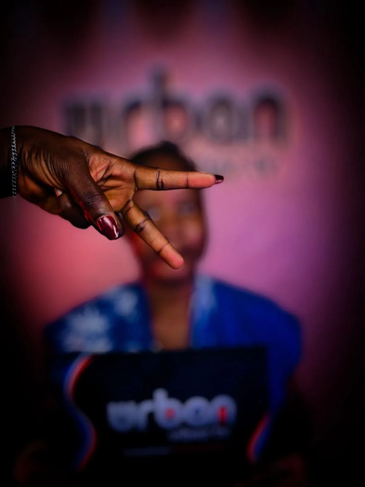 Artistic close-up of a peace-sign hand against the branded backdrop