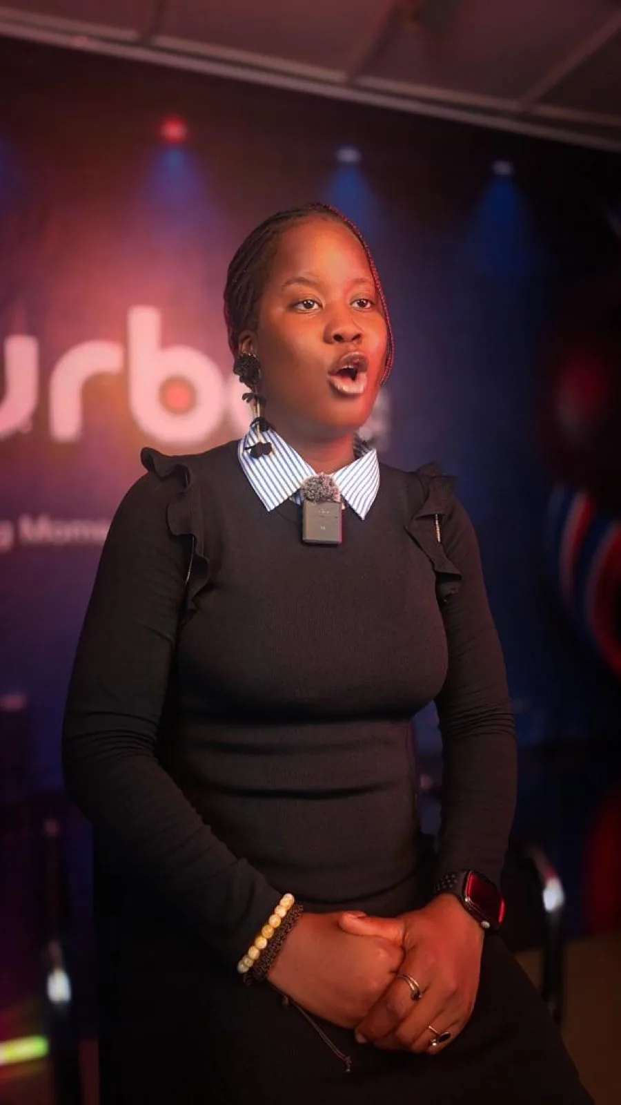 Presenter in a black top speaking to camera