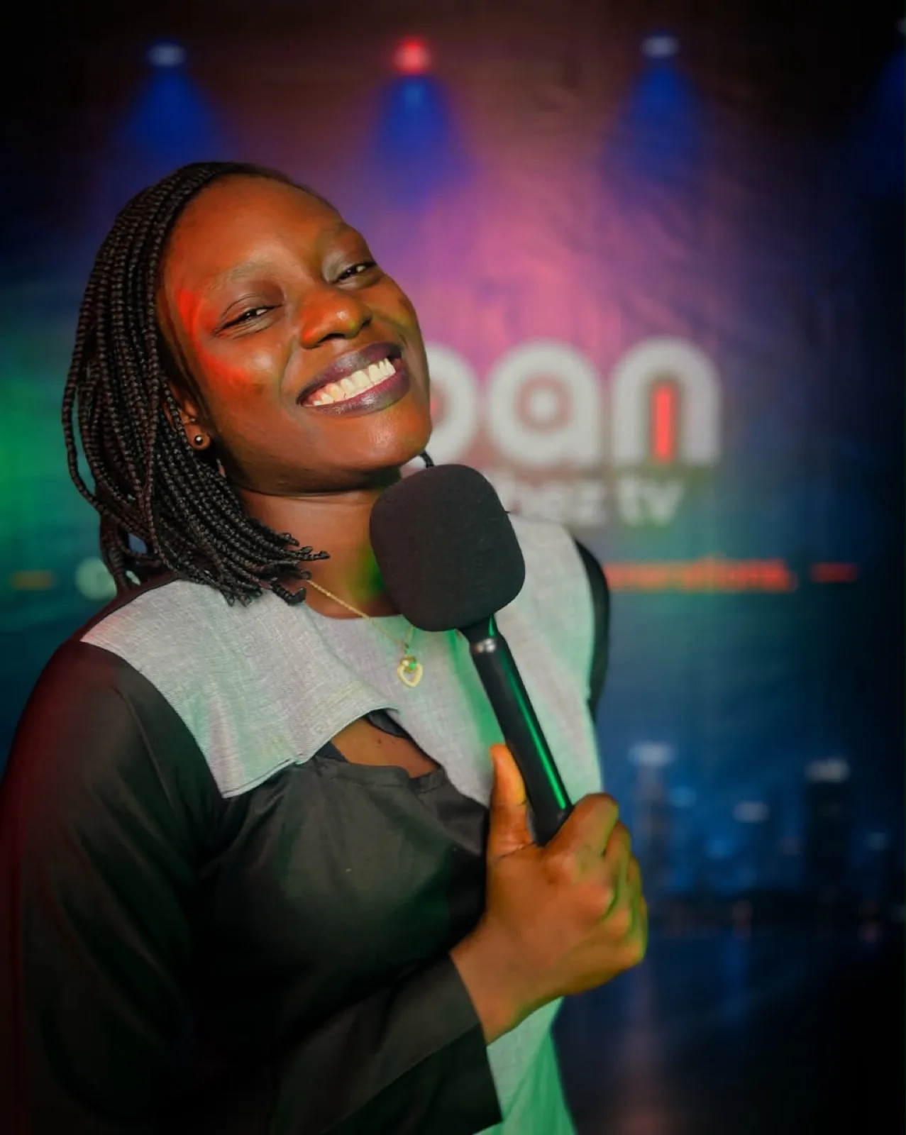 Presenter smiling with a microphone under studio lights