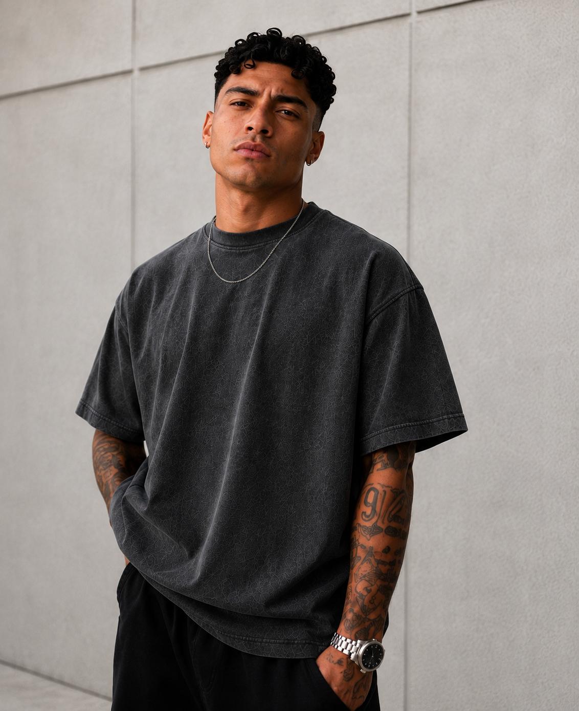 A man in an oversized black tee crossing a street at dusk.