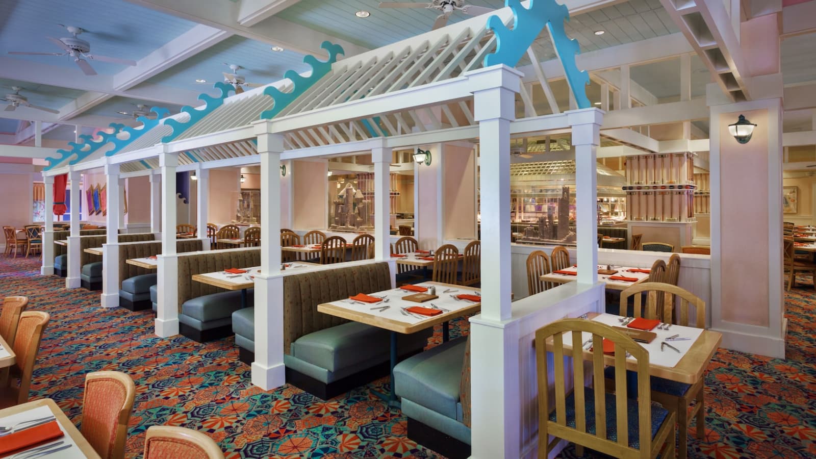 Dining room at Cape May Cafe in Disney's Beach Club Resort with white trellis booths topped by blue wave trim and beach umbrella carpet