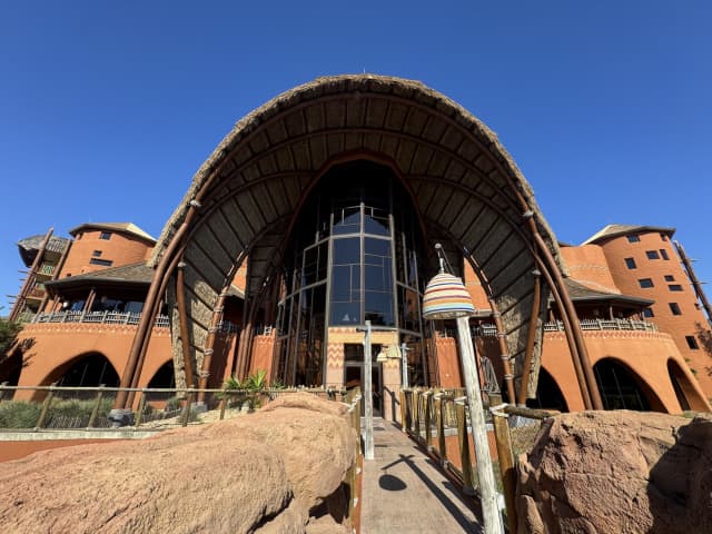 The dramatic thatched arch entrance of Kidani Village at Disney's Animal Kingdom Lodge against a clear blue sky