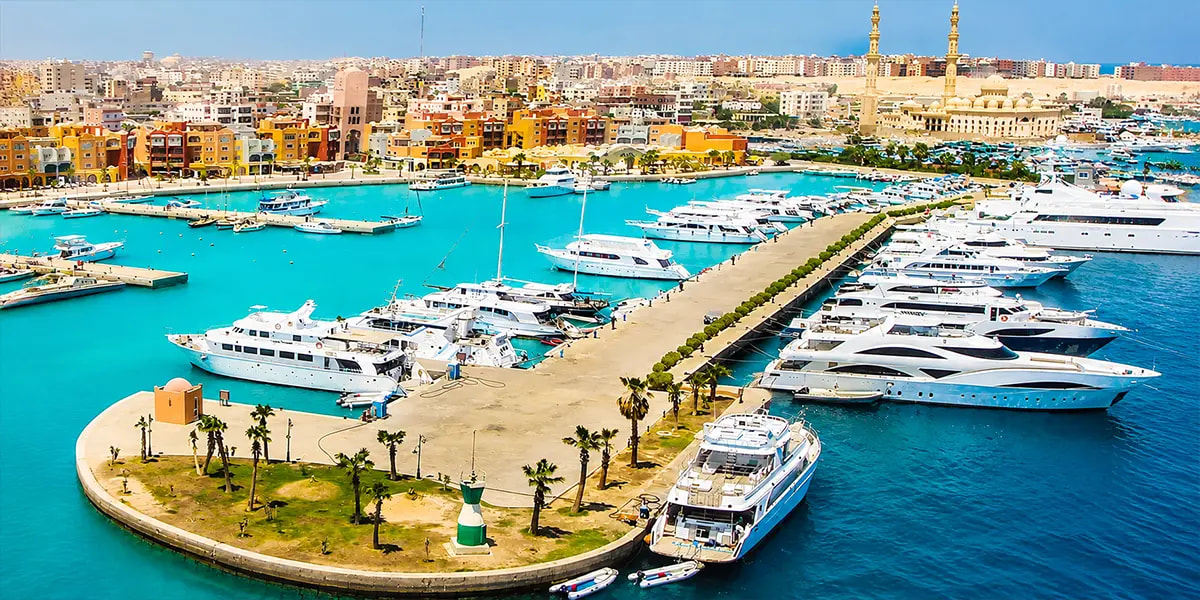 Hurghada Marina featuring yachts, restaurants, and tourists, highlighting the year-round tourism that drives rental demand in Hurghada property investment.