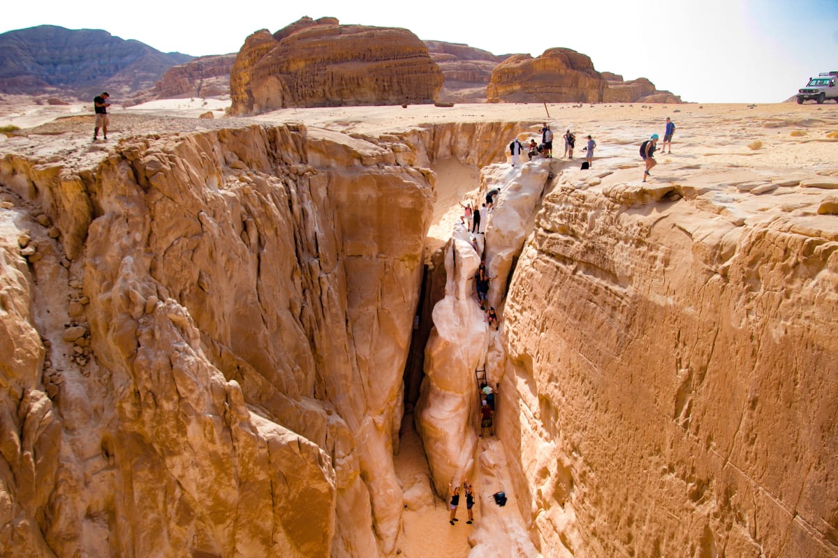 Travel group rock climbing in a rock crevice in the desert.