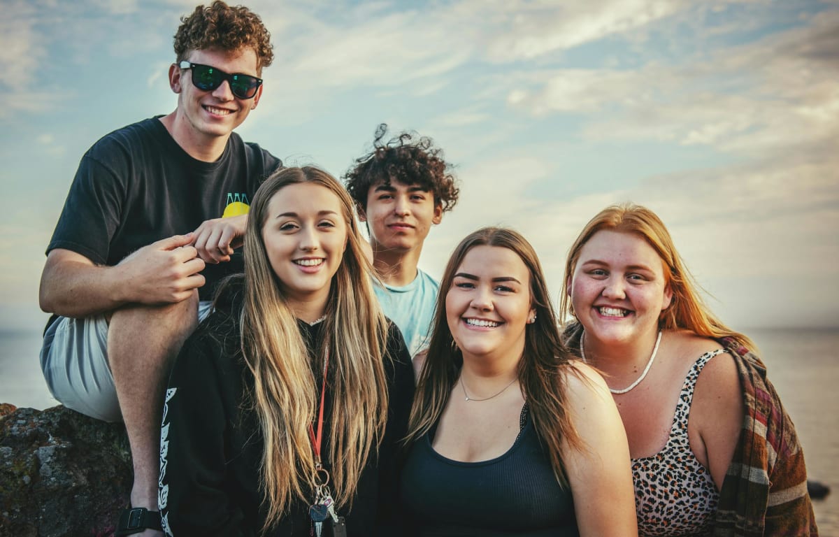 Group of 3 young women and 2 younf boys, who all laughed at the camera as they have been looking for finding travel buddy.