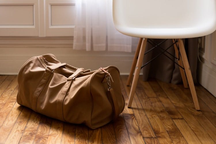 a packed bag lying on the floor, next to a chair 