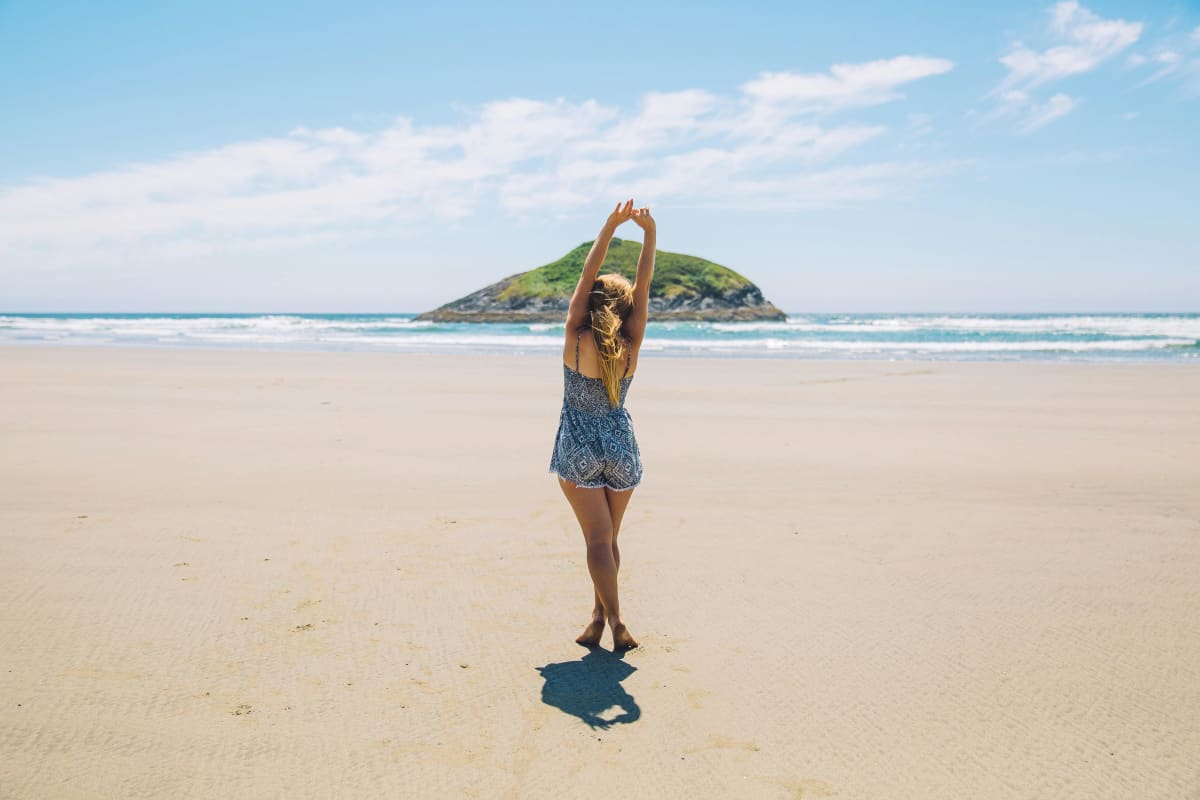 girl holding up her arms on the beach 