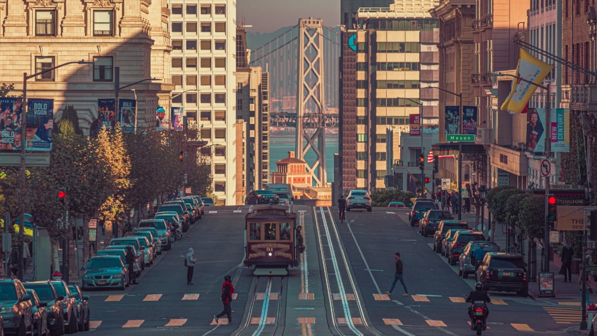 View of a street in San Francisco with view of the harbor and a cable car.