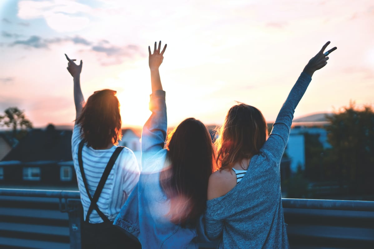 three girls standing with their arms in the air 