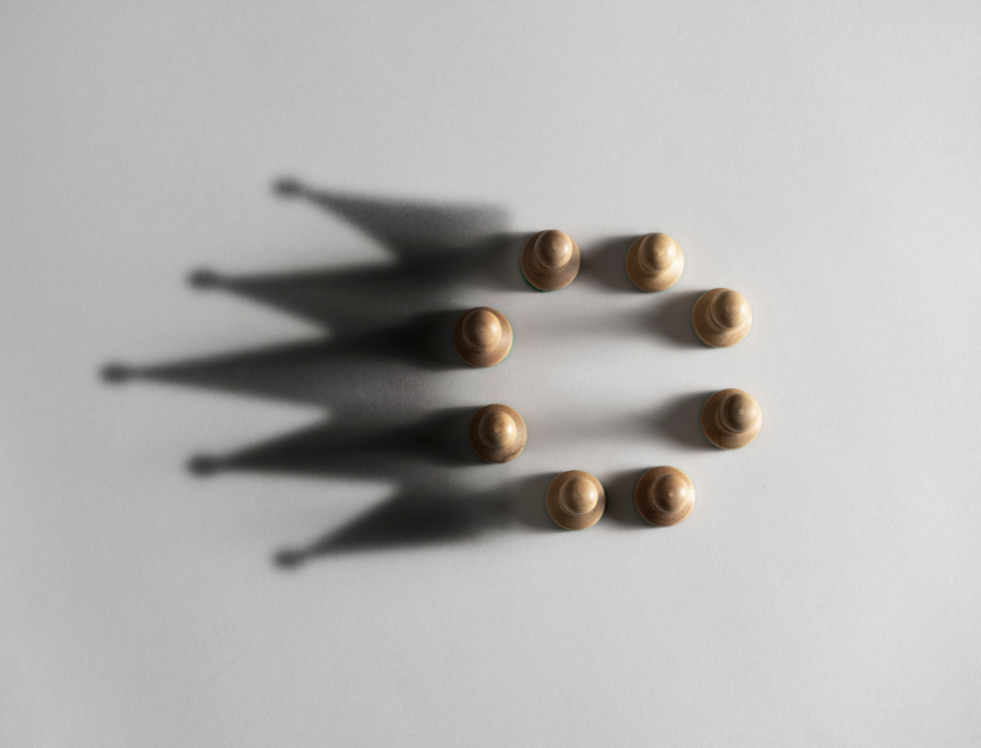 Eight small wooden pieces arranged in a ring on a pale surface, each one casting a long shadow across it