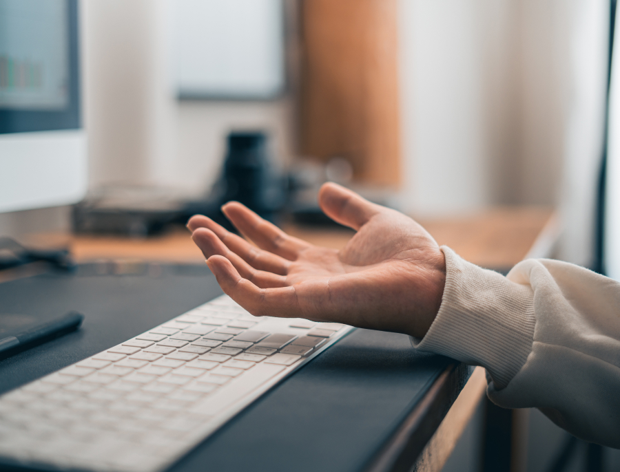 An open hand resting beside a keyboard at a desk, paused mid gesture