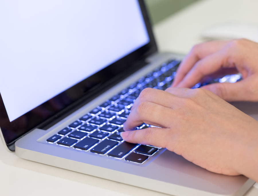 Close up of two hands typing on a laptop keyboard, the screen out of frame and not legible