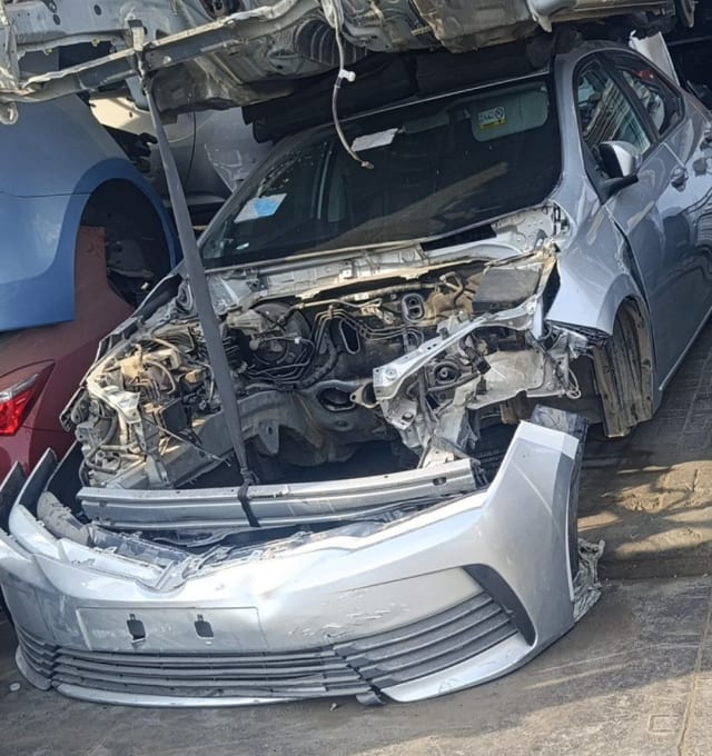 Silver Toyota Corolla sedan halfcut — detached front bumper, exposed engine bay and fender, Sharjah market