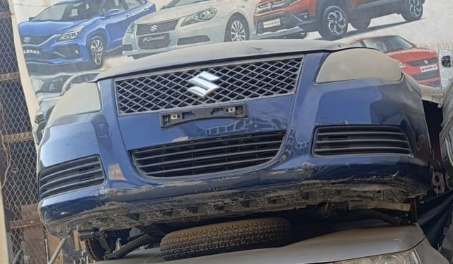 Dark blue Suzuki Kizashi sedan front cut — bumper and mesh grille with Suzuki badge, Sharjah market