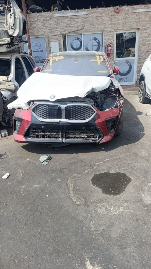 Red BMW X2 crossover front-end damage — grille, front bumper and deployed airbag, Sharjah market