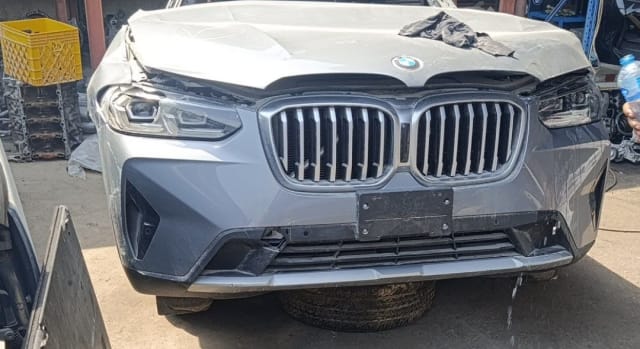 Silver BMW X3 SUV front halfcut — kidney grille, headlights, bumper and damaged hood, Sharjah market