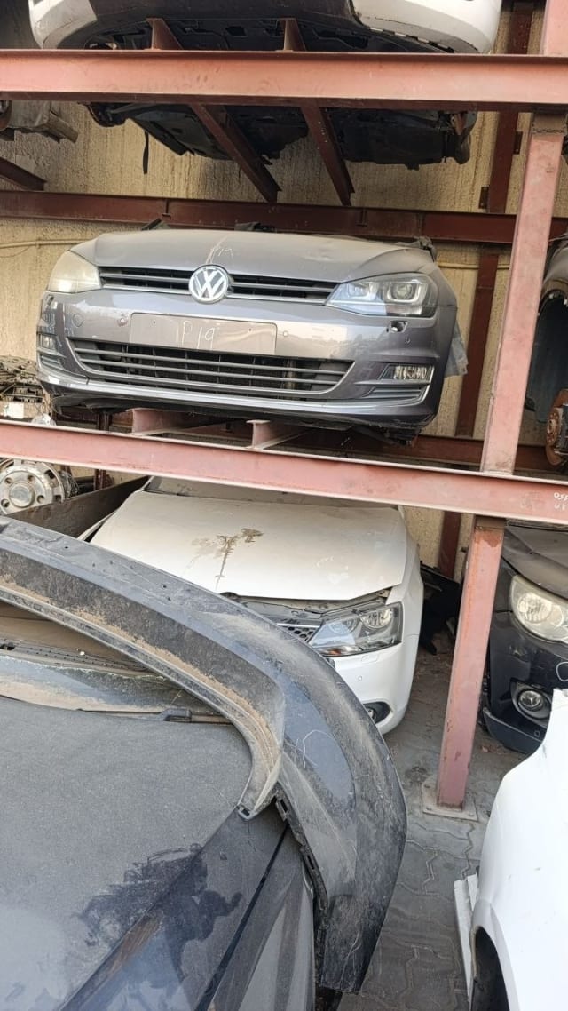 Dark grey Volkswagen Golf front halfcut — bumper, grille, headlights and hood on a parts rack, Sharjah market