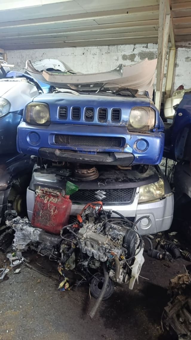 Blue Suzuki Jimny SUV front cut — bumper, twin headlights and grille with loose engine, Sharjah market