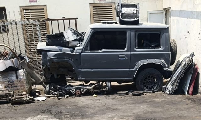 Grey Suzuki Jimny 3-door SUV halfcut with doors, glass, alloy wheels and scattered suspension parts, Sharjah market