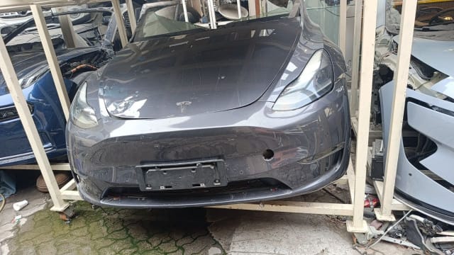 Dark grey Tesla Model Y front halfcut — bumper, hood and headlights on rack, Sharjah market