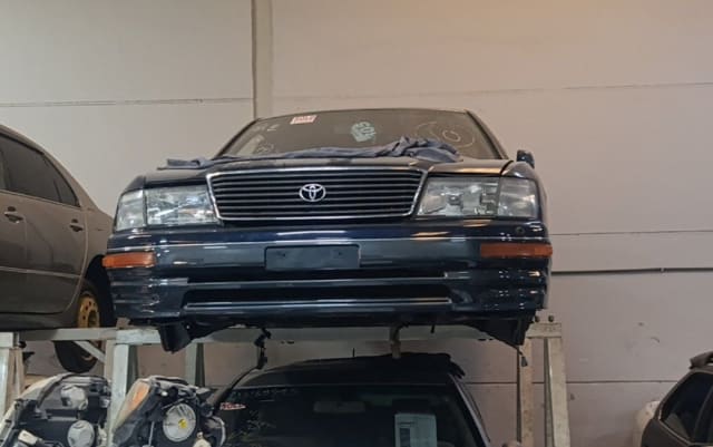 Dark blue Toyota Celsior sedan front halfcut — bumper, grille and headlights on rack, Sharjah market