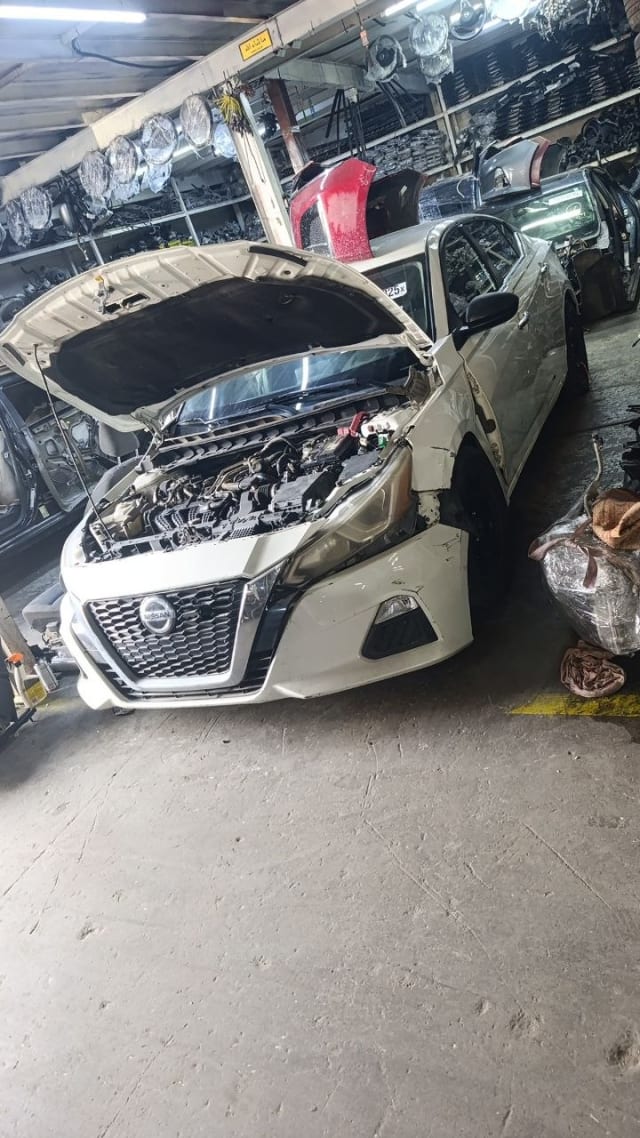 White Nissan Altima sedan halfcut — open hood, front bumper, grille and engine bay, Sharjah market