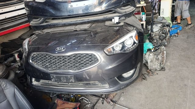 Dark grey Kia Cadenza sedan front halfcut — bumper, grille and headlights, Sharjah market